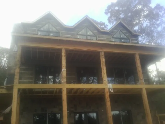 Dormers and porch framing on a large log home under construction — Roof Coating work by our crew in New Bloomfield