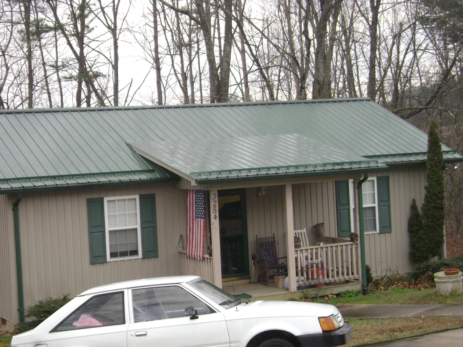 Green metal roof and front porch on a tan sided cottage in New Bloomfield