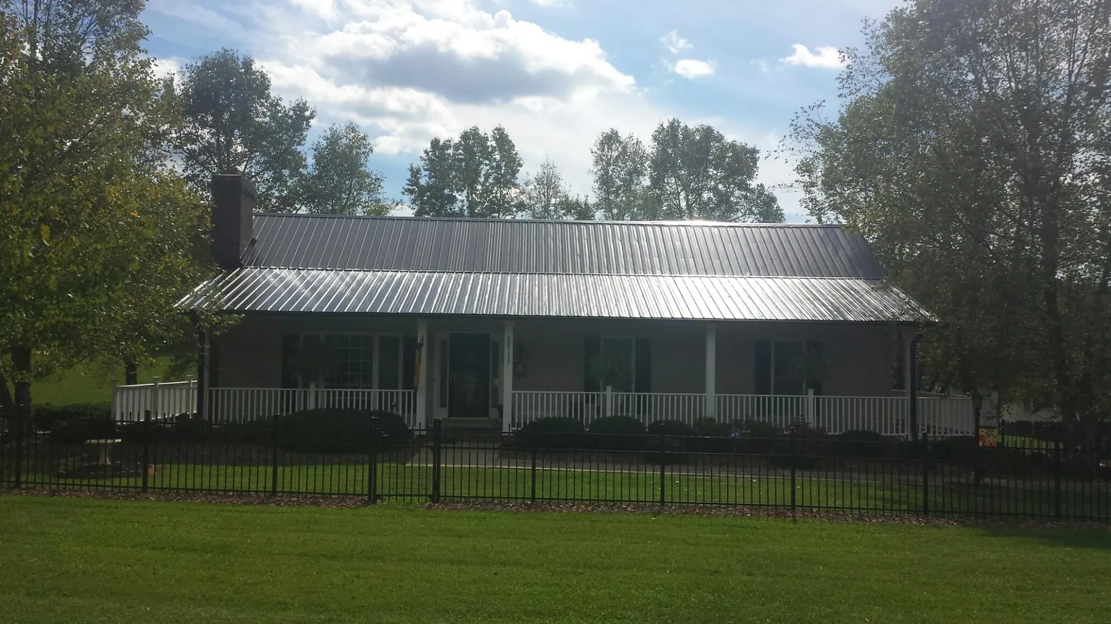 Gray metal roof on a brick ranch with a full width front porch — Gutter Guard Installation work by our crew in New Bloomfield
